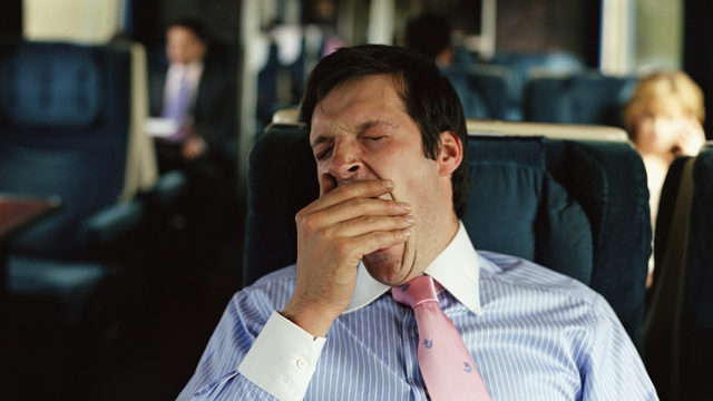 Businessman yawning on train (focus on man)